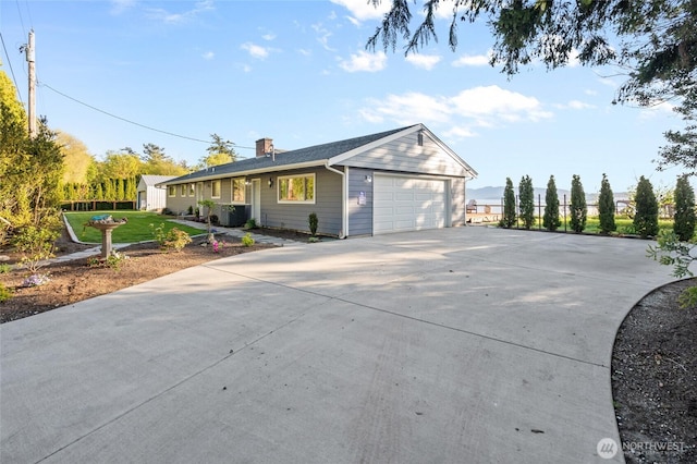 view of front facade with a garage, central AC unit, driveway, and a chimney
