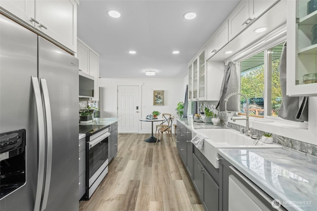 kitchen with white cabinets, stainless steel fridge, light wood-style floors, range with electric cooktop, and recessed lighting