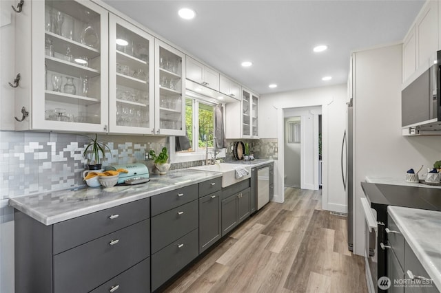 kitchen featuring a sink, light wood-style floors, dishwasher, range with electric cooktop, and white cabinetry