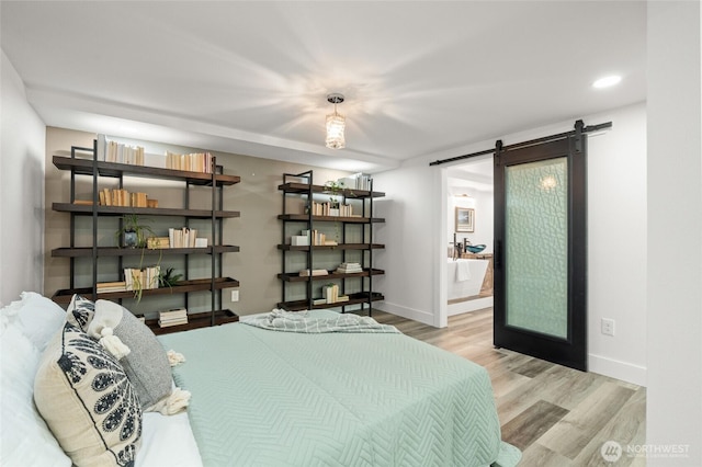 bedroom with baseboards, recessed lighting, a barn door, and wood finished floors