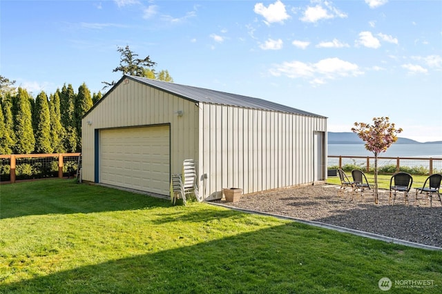 detached garage with a water view and fence