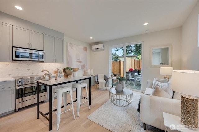 living room with recessed lighting, light wood-style floors, and a wall mounted air conditioner