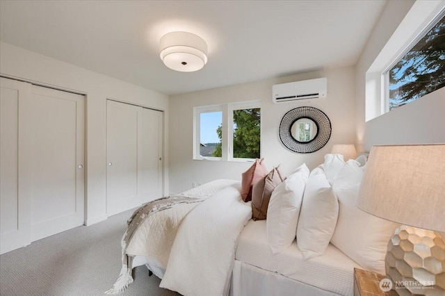 carpeted bedroom featuring multiple closets and a wall unit AC