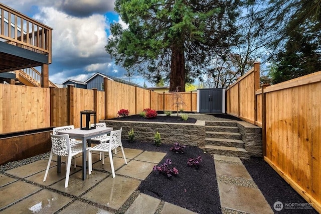 view of patio featuring outdoor dining space, a storage shed, a fenced backyard, and an outdoor structure
