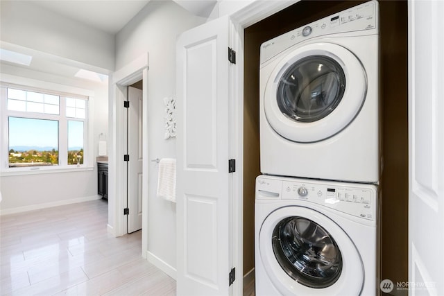 3048 39th Ave W, Seattle, WA 98199 - washroom with laundry area, baseboards, stacked washing maching and dryer, and light wood-style floors