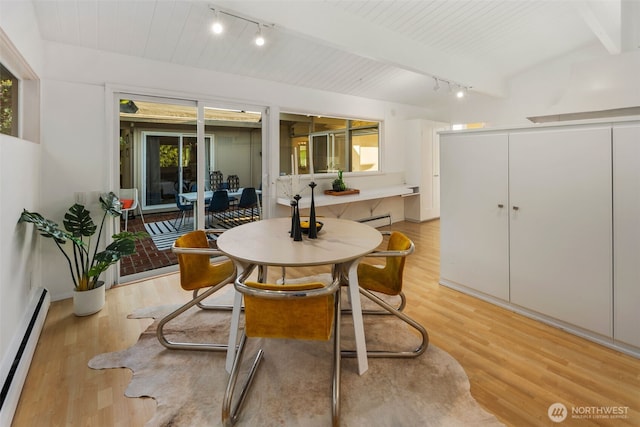 dining area with track lighting, a baseboard heating unit, baseboard heating, and light wood-type flooring