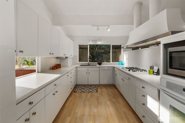 kitchen featuring a sink, light countertops, light wood finished floors, and white appliances