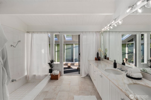 full bath with a shower with shower curtain, beamed ceiling, plenty of natural light, and a sink