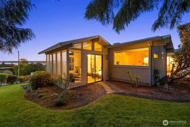 back of house at dusk with a lawn
