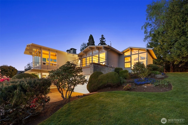 view of front of home with an attached garage, a front lawn, a balcony, and driveway