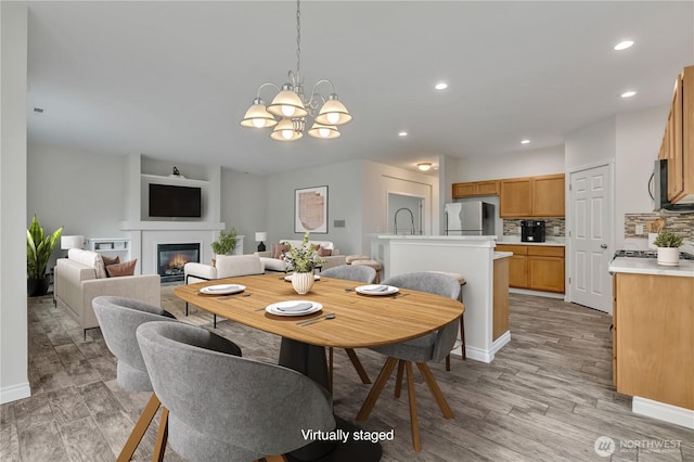 24204 SE 278th St, Maple Valley, WA 98038 - dining area with a glass covered fireplace, light wood finished floors, a chandelier, recessed lighting, and baseboards