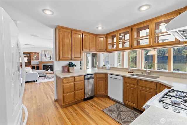 kitchen with light wood-style floors, a sink, white appliances, and light countertops
