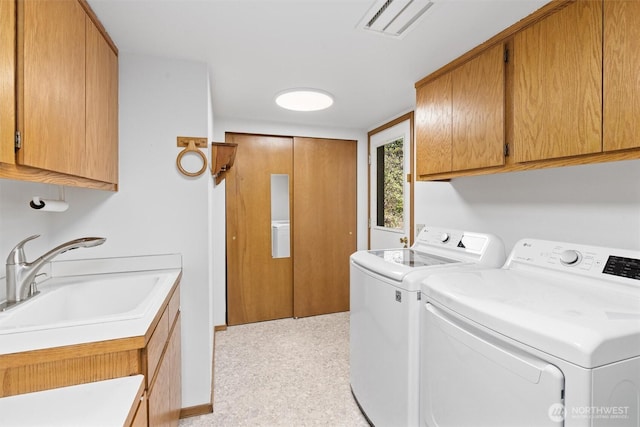 laundry area with a sink, washing machine and dryer, baseboards, visible vents, and cabinet space