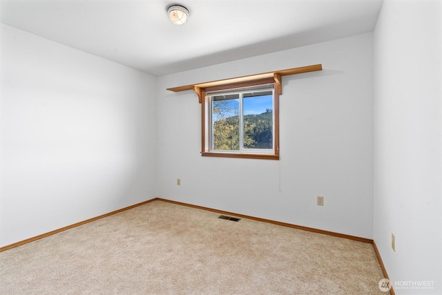 carpeted empty room featuring baseboards and visible vents