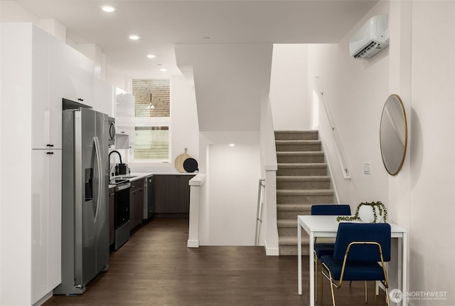kitchen featuring stainless steel refrigerator with ice dispenser, range with electric cooktop, a wall mounted air conditioner, dark wood finished floors, and recessed lighting