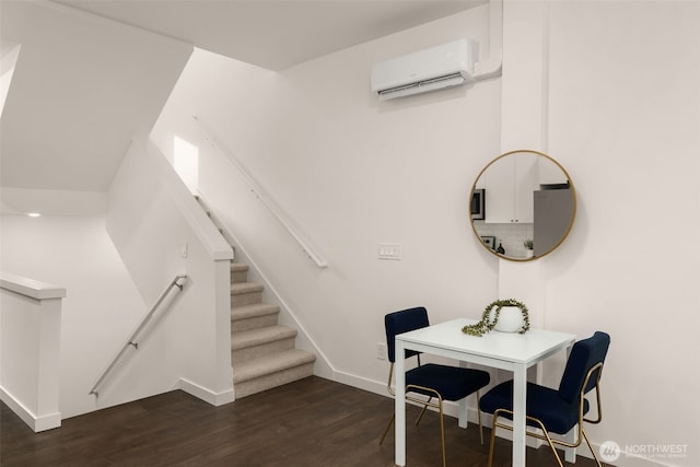 interior space with an AC wall unit, baseboards, and wood finished floors