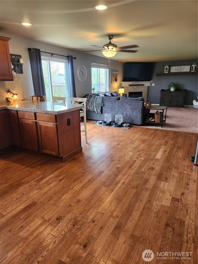 9244 Carys St SE, Yelm, WA 98597 - kitchen with ceiling fan, a peninsula, hardwood / wood-style floors, and brown cabinets