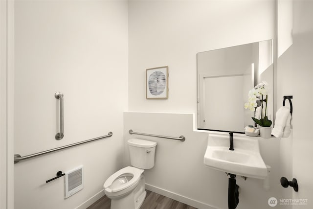 half bathroom featuring baseboards, a sink, toilet, and wood finished floors