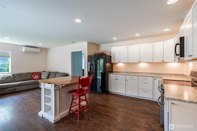 876 1st St, Chelan Falls, WA 98817 - kitchen featuring black appliances, open floor plan, dark wood-type flooring, a wall mounted AC, and white cabinetry