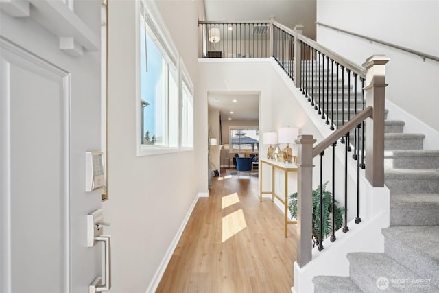entryway featuring baseboards, wood finished floors, a towering ceiling, and stairs