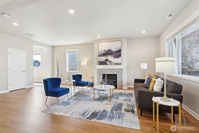 living area featuring wood finished floors, a tiled fireplace, visible vents, and a wealth of natural light