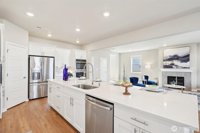 kitchen featuring open floor plan, light countertops, white cabinets, appliances with stainless steel finishes, and a sink