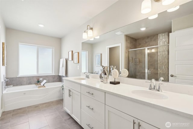 bathroom featuring a stall shower, a garden tub, a sink, and tile patterned flooring
