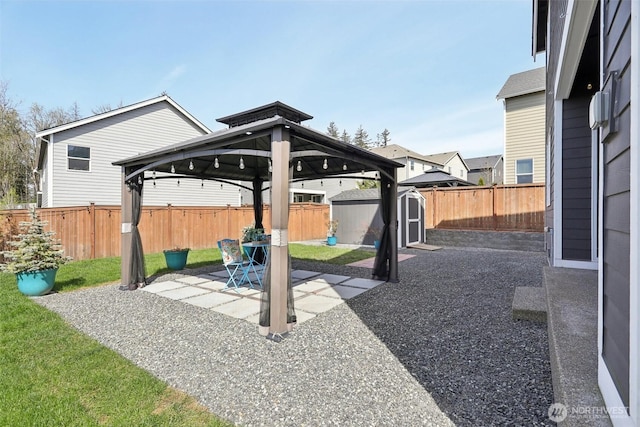view of patio / terrace featuring a gazebo, a storage shed, a fenced backyard, and an outdoor structure