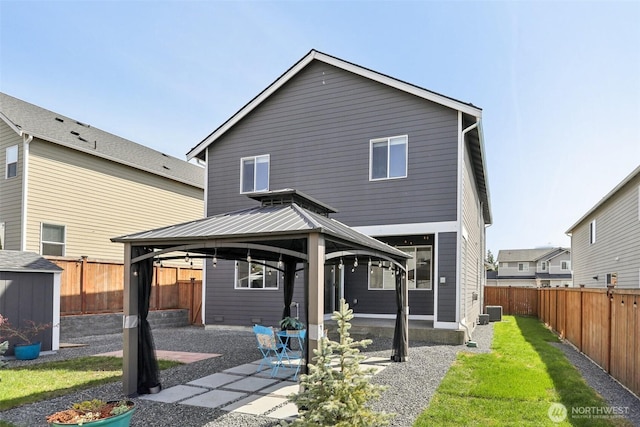 rear view of house with a fenced backyard, a gazebo, a patio, and a lawn