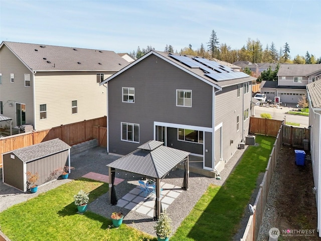 back of house with solar panels, a patio area, a lawn, and a fenced backyard