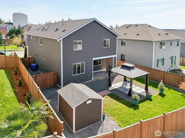 rear view of property with a gazebo, a patio area, a fenced backyard, and an outbuilding
