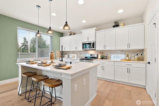 14232 SE 284th Pl, Kent, WA 98042 - kitchen featuring decorative backsplash, a kitchen island with sink, light wood-style floors, and appliances with stainless steel finishes