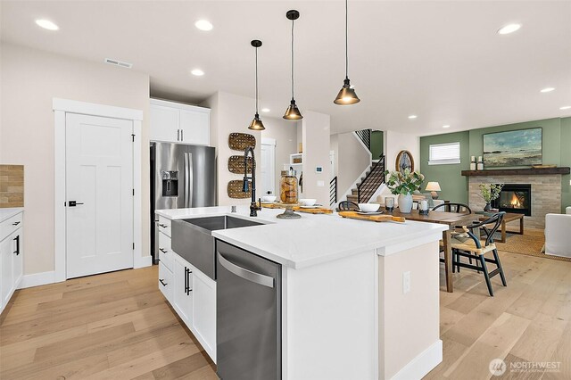 14232 SE 284th Pl, Kent, WA 98042 - kitchen with appliances with stainless steel finishes, a glass covered fireplace, visible vents, and light wood finished floors
