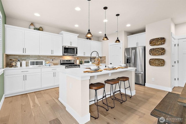 14232 SE 284th Pl, Kent, WA 98042 - kitchen featuring light countertops, stainless steel appliances, a center island with sink, light wood finished floors, and backsplash