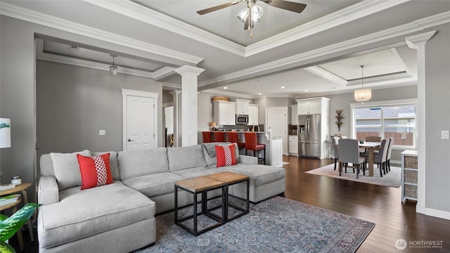 131 NW Blalock Dr, College Place, WA 99324 - living area featuring dark wood-style flooring, ceiling fan, crown molding, a tray ceiling, and ornate columns