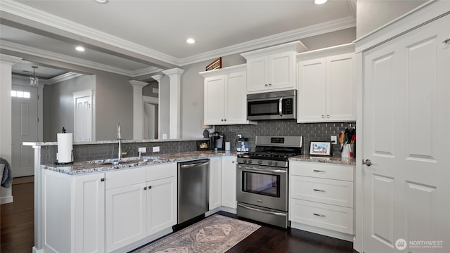 131 NW Blalock Dr, College Place, WA 99324 - kitchen featuring a sink, dark wood-style flooring, appliances with stainless steel finishes, decorative columns, and a peninsula