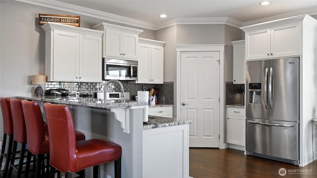 131 NW Blalock Dr, College Place, WA 99324 - kitchen featuring a breakfast bar, recessed lighting, a peninsula, white cabinets, and appliances with stainless steel finishes