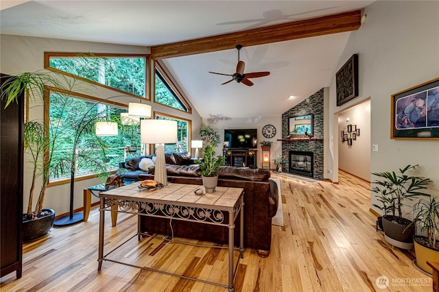 living room with light wood-style floors, a stone fireplace, a ceiling fan, and beam ceiling