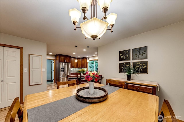 dining space featuring recessed lighting, light wood-type flooring, and an inviting chandelier