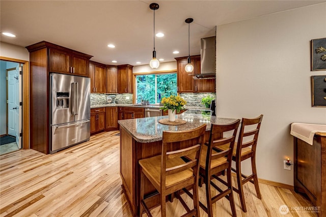 kitchen with stone counters, light wood-type flooring, decorative backsplash, stainless steel appliances, and a sink