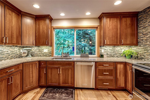 kitchen featuring tasteful backsplash, a sink, light wood-type flooring, brown cabinets, and stainless steel appliances