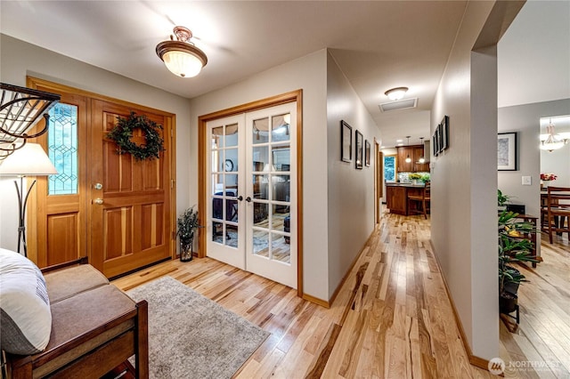 foyer with french doors, light wood-style flooring, and baseboards