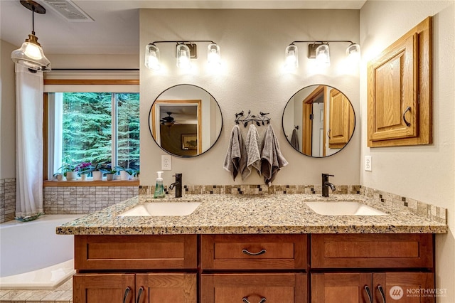 full bathroom with a garden tub, double vanity, a sink, and visible vents