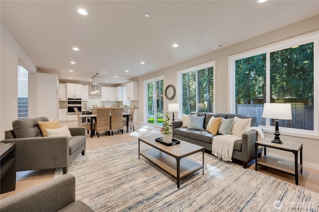 living room with baseboards, light wood-style floors, visible vents, and recessed lighting