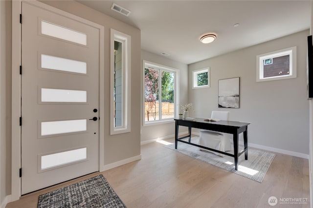 foyer entrance with visible vents, light wood finished floors, and baseboards