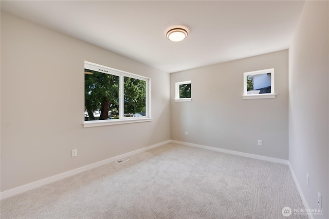 carpeted spare room with visible vents, baseboards, and a wealth of natural light
