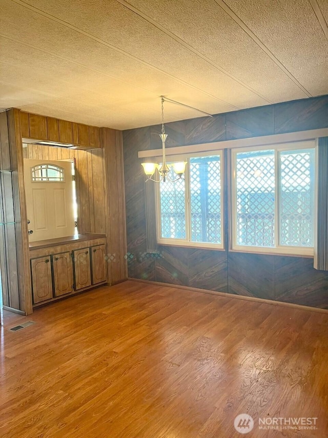 815 124th St SW Unit 144, Everett, WA 98204 - unfurnished dining area featuring wood walls, wood finished floors, visible vents, a textured ceiling, and a notable chandelier