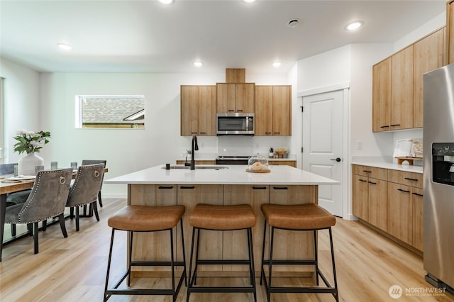 709 E 5th St, Nooksack, WA 98276 - kitchen with a kitchen island with sink, a kitchen breakfast bar, light wood-type flooring, a sink, and stainless steel appliances