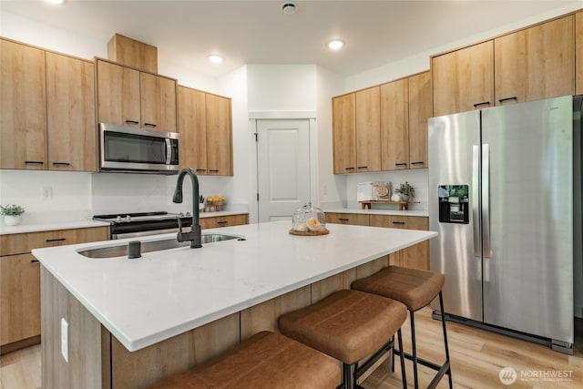 709 E 5th St, Nooksack, WA 98276 - kitchen featuring appliances with stainless steel finishes, a sink, light wood finished floors, a breakfast bar area, and light countertops