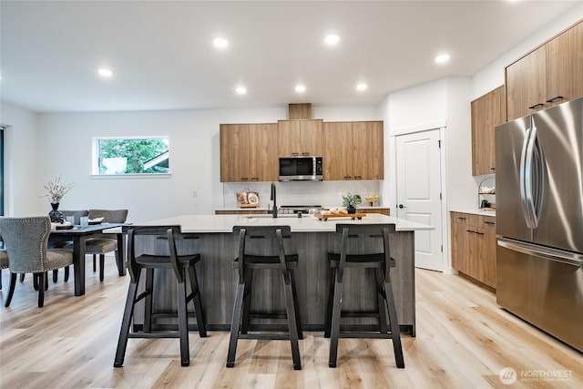 710 E 5th St, Nooksack, WA 98276 - kitchen with light countertops, a kitchen breakfast bar, brown cabinets, and stainless steel appliances